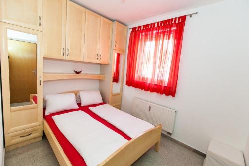 a small bedroom with a bed and a red window at Apartment Crikvenica, Vinodol in Sopaljska