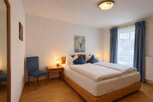 a bedroom with a large bed and a blue chair at Tivoli Apartments in Bad Reichenhall