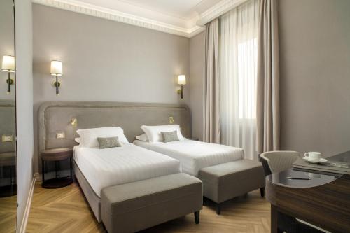 a hotel room with two beds and a chair at Aria Palace by OMNIA hotels in Rome
