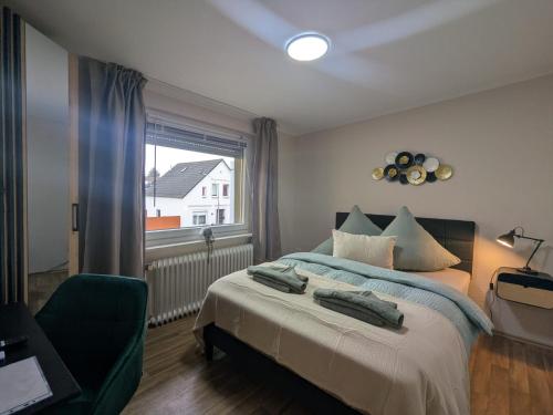 a bedroom with a bed with a green chair and a window at STEP IN Apartments ! in Wilhelmshaven