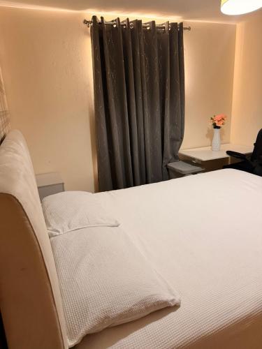 a bedroom with a white bed with a black curtain at Springfield garden-Celtic park in Glasgow