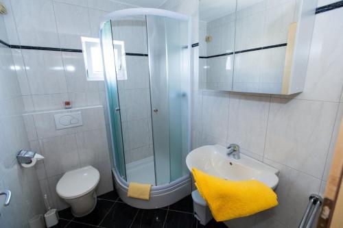 a bathroom with a sink and a shower with a yellow towel at Apartment Crikvenica 15 in Sopaljska