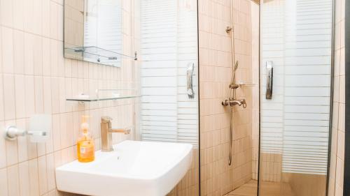 a white bathroom with a sink and a shower at 3Apartments in Lagos