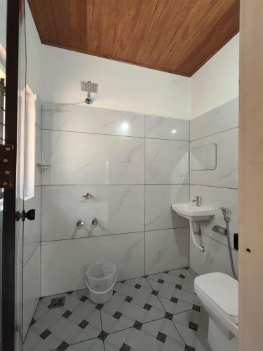 a white bathroom with a sink and a toilet at Riverwood Cottages in Kallar Vattiyar