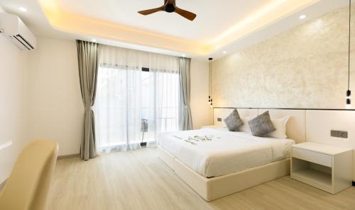 a bedroom with a white bed and a window at Kirulhiya Omadhoo - Live the Island Dream in Omadhoo
