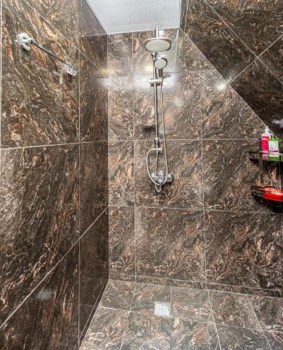 a bathroom with a shower with a brown marble wall at Veranda Buknari in Buknari