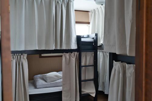 a group of bunk beds in a room with curtains at IZA Kamakura Guest House and Bar in Kamakura