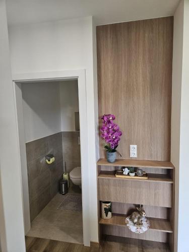 a bathroom with a toilet and a vase with purple flowers at Ferienwohnung 2 am Gleichenberger "Kogl" in Bad Gleichenberg