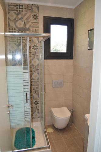 a bathroom with a shower and a toilet and a window at Arethousa House in Nea Vrasna