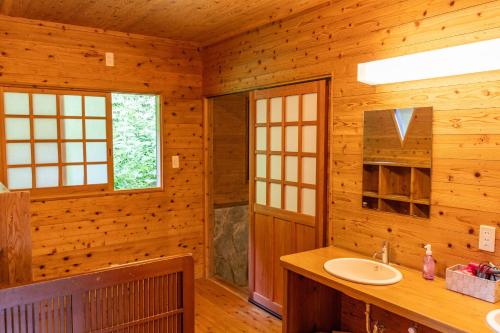 ein Badezimmer mit Waschbecken in einer Holzhütte in der Unterkunft 阿蘇扇温泉 おおぎ荘 in Minamioguni