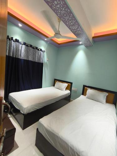 two beds in a room with blue walls at Hotel Pink Orchid in Chittagong