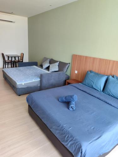 a bedroom with two beds with a blue teddy bear on it at Sematan Roxy Beach Apartment in Sematan