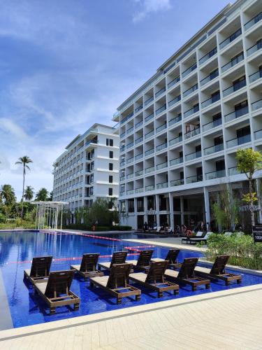 a hotel swimming pool with lounge chairs in front of a building at Sematan Roxy Beach Apartment in Sematan