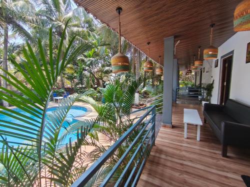 a balcony of a house with a pool and palm trees at Sarovar Morjim in Morjim