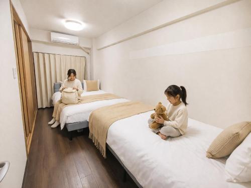 two little girls sitting on beds in a room at Sengakuji 603, 40 square meters house Direct train from the airport in Tokyo