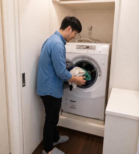 a man loading a washing machine in a room at Sengakuji 603, 40 square meters house Direct train from the airport in Tokyo