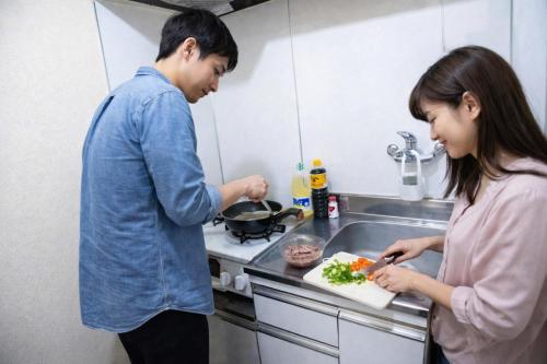 a man and woman in the kitchen preparing food at Sengakuji 603, 40 square meters house Direct train from the airport in Tokyo