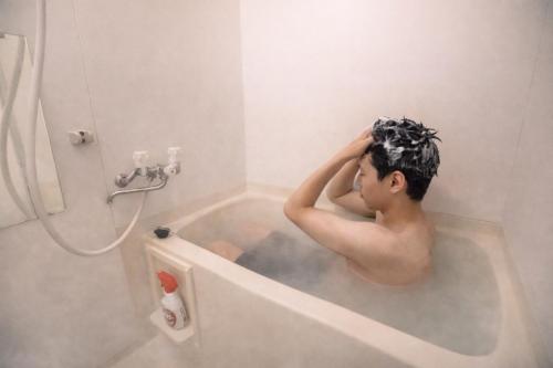 a man is sitting in a bath tub at Sengakuji 603, 40 square meters house Direct train from the airport in Tokyo