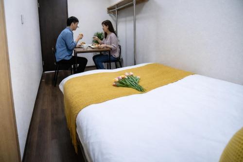 a man and woman sitting at a table in a hotel room at Sengakuji 603, 40 square meters house Direct train from the airport in Tokyo