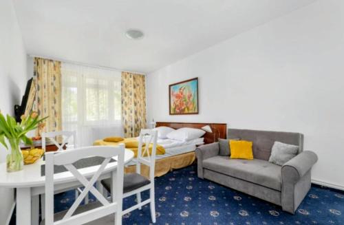 a bedroom with a bed and a couch and a table at M-Apartamenty in Kołobrzeg