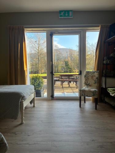 a bedroom with a bed and a sliding glass door at The Hermitage Riverside House in Clogheen
