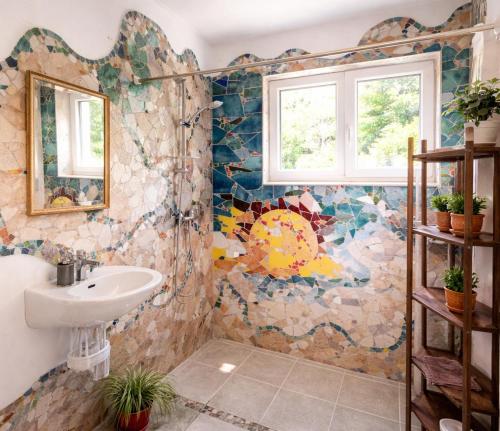 a bathroom with a sink and a mosaic wall at Art house Tufi in Bistrica ob Sotli