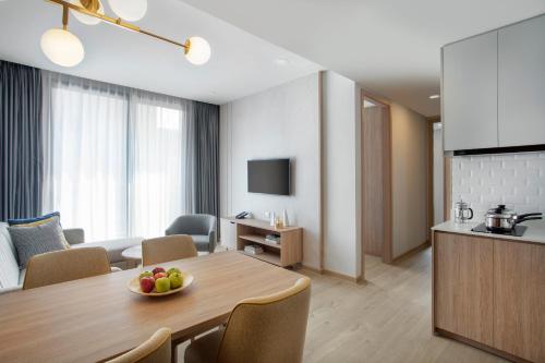 a living room with a dining table and a kitchen at Staybridge Suites Bangkok Thonglor by IHG in Bangkok