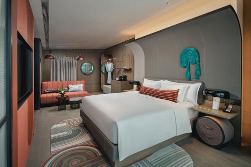 a bedroom with a large white bed and a living room at Hotel Indigo Ningbo Riverside by IHG in Ningbo