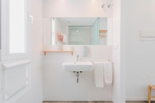 a white bathroom with a sink and a mirror at Hostal La Isla in Carboneras