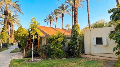 a house with palm trees in front of it at Nir David Country Lodge in Nir Dawid