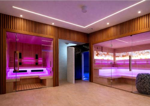 a bathroom with pink lighting and glass walls at Piastun SPA&Wellness Krynica-Zdrój in Krynica Zdrój