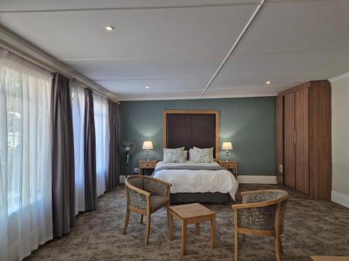 a hotel room with a bed and two chairs at Milner Manor in Grahamstown