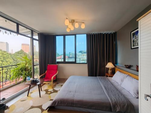 a bedroom with a large bed and a red chair at T Home Balcony in Hanoi