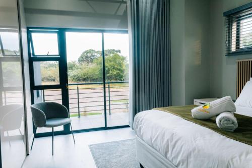 a bedroom with a bed and a chair and a window at Villa Limonero in Naboomspruit