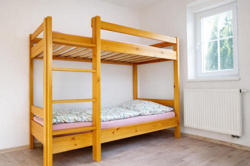 a wooden bunk bed in a room with a window at Symbiola Holiday House in Arnoltice u Decina