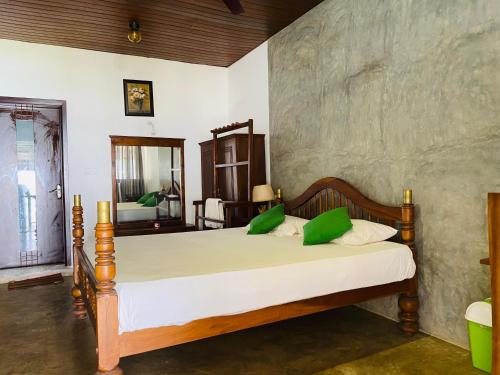 a bedroom with a bed with green pillows at Amadio Beach Resort in Hikkaduwa