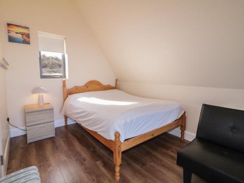 a small bedroom with a bed and a chair at Cabin 6 An Mhucais in Gortahork