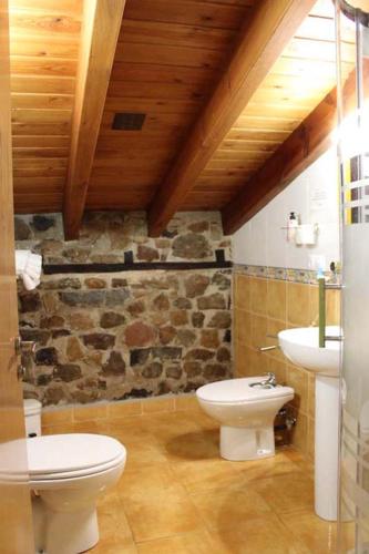 a bathroom with a white toilet and a sink at Apartamentos La Barcenilla in Herada