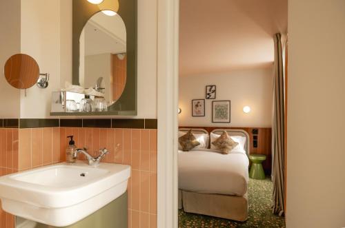 a bathroom with a sink and a bed with a mirror at Salvia Paris in Paris