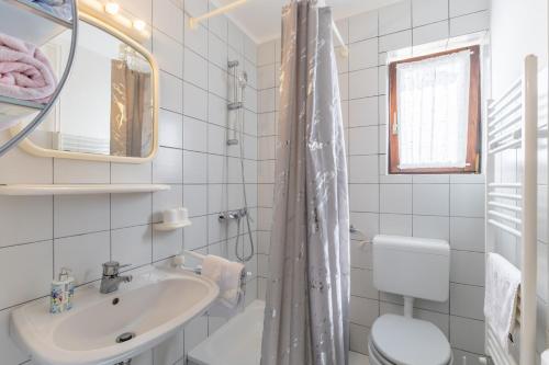 a bathroom with a sink and a toilet and a mirror at Apartments Koraca in Poreč