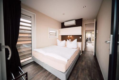 a bedroom with a large white bed with a window at Floatinghouse Hideaway LP26 in Klitten