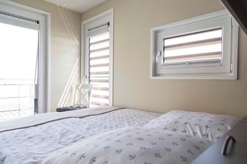 a bedroom with a bed and two windows at Floatinghouse Möwenblick - LP1 in Vetschau