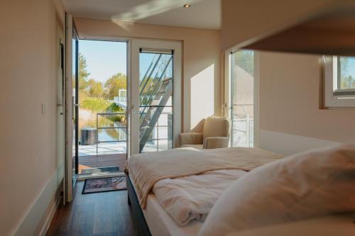 a bedroom with a bed and a sliding glass door at Floatinghouse Seelenbaumler - LP13 in Vetschau