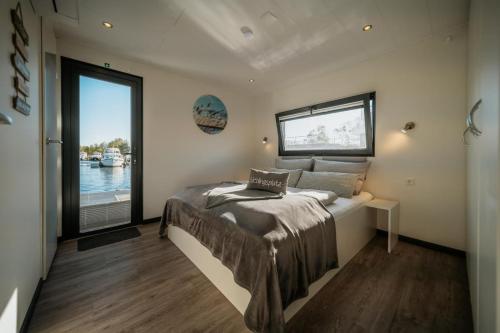 a bedroom with a bed and a large window at Floatinghouse Red Pearl in Zehdenick