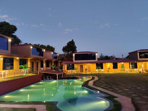 a swimming pool in front of a house at night at Arya Resort And Spaa in Mahabaleshwar