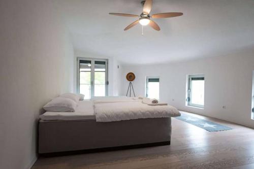 a white bedroom with a bed and a ceiling fan at Villa Boomerang in Srbljani