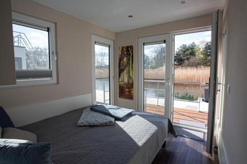 a bedroom with a bed and a balcony with windows at Floatinghouse Dolce Vita - LP10 in Vetschau