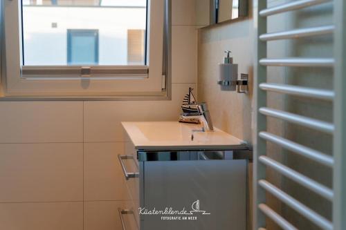 a small bathroom with a sink and a window at Floatinghouse Arielle in Ribnitz-Damgarten
