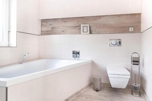 a white bathroom with a tub and a toilet at Floatinghouse Möwe 1 - LP1 in Vetschau