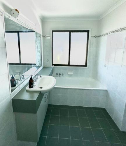 a white bathroom with a sink and a bath tub at Waterfront Retreat Mooloolaba in Mooloolaba